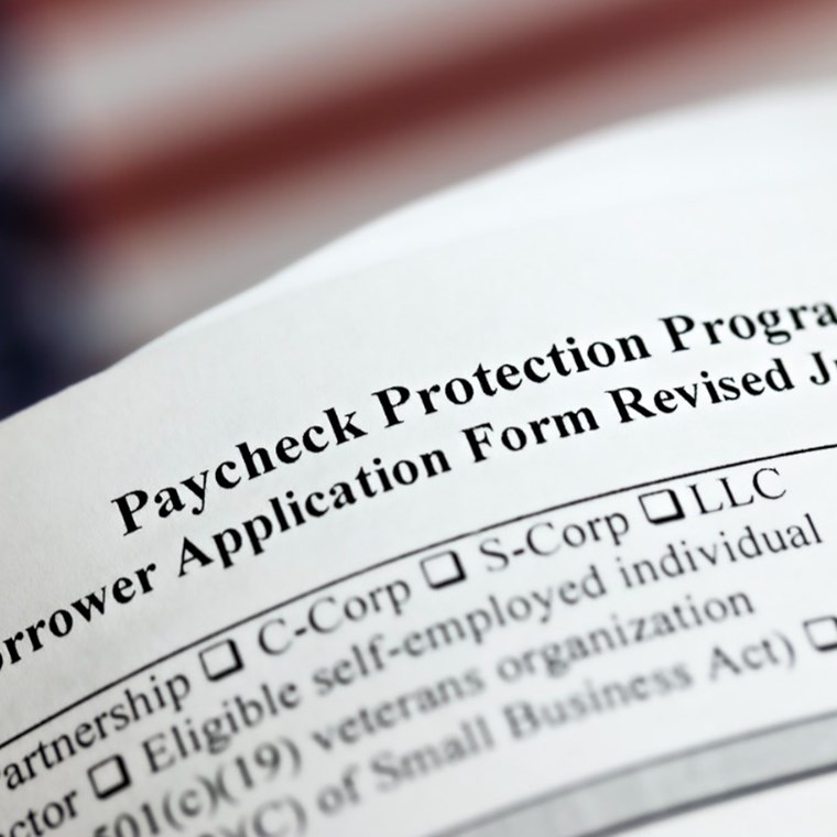 Selective focus photo of paycheck protection program borrower application form revised, on a background of United States flag. paycheck protection program new round. stock photo