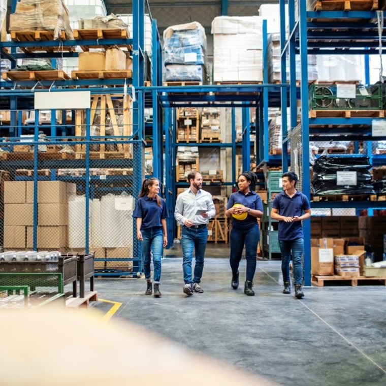 Warehouse employees walking through aisle and talking stock photo