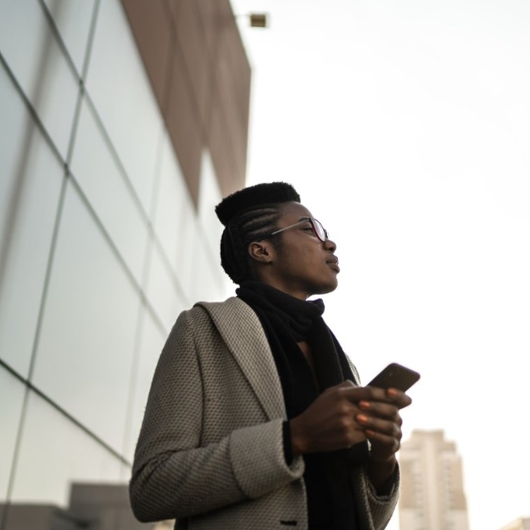Young businesswoman using mobile phone and looking away at office rooftop stock photo